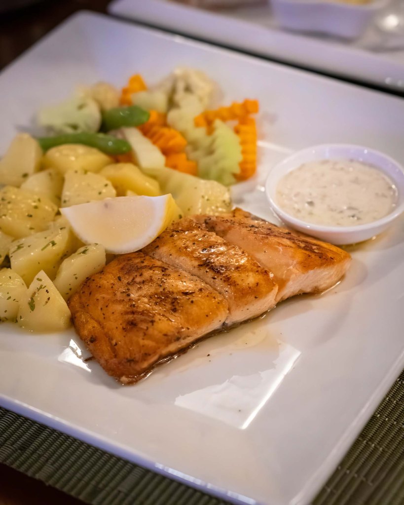 Fresh pan-seared salmon fillet served with boiled potatoes and steamed vegetables at TipTop Hotel and Resto.