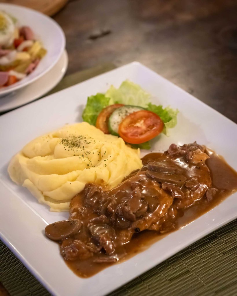 Traditional Vienna-style breaded Schnitzel topped with mushroom gravy and served with creamy mashed potatoes at TipTop Bohol.