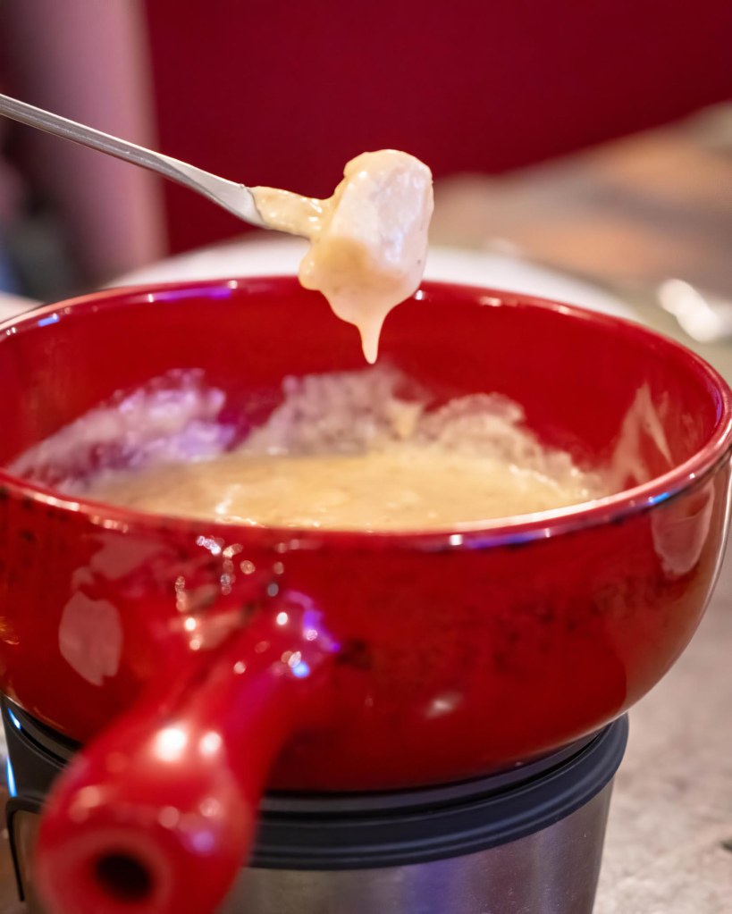 Traditional Swiss Cheese Fondue in a red ceramic pot, a signature communal dining experience at TipTop Panglao.