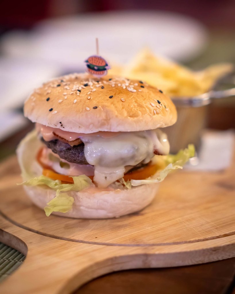 The signature TipTop Burger featuring a thick beef patty, melted cheese, and fresh greens on a toasted sesame bun.