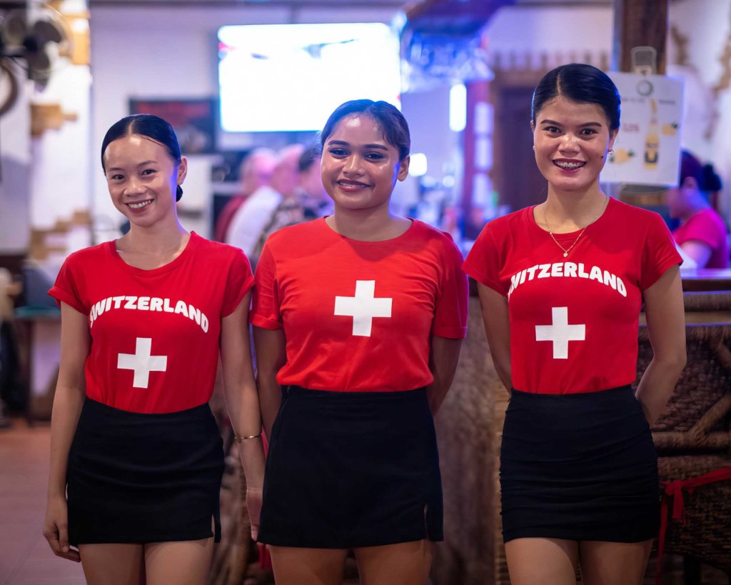 Friendly staff at TipTop Resto wearing Switzerland-themed uniforms, highlighting the authentic Swiss hospitality in Panglao.